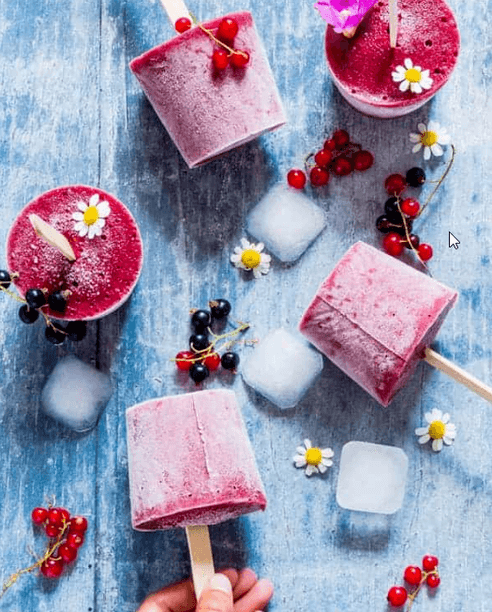 Popsicles on a table with fruit and ice cubes