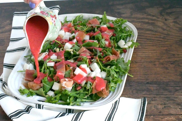 Jicama salad on a platter with raspberry vinaigrette being drizzled 