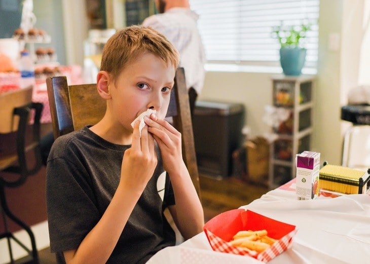 Boy eating and wiping his mouth