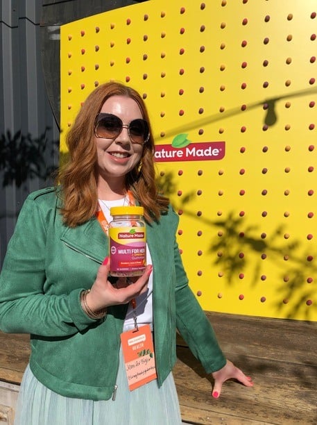 Jennifer Bigler standing with a bottle of Nature Made vitamins